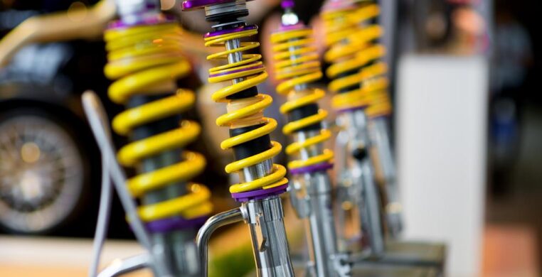 Mechanic fitting a new car suspension system in a Nottingham garage, showing shock absorbers and springs being installed for improved ride quality.